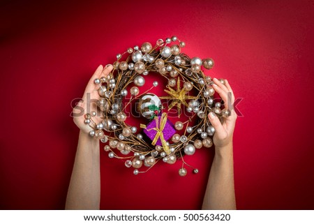 Christmas decorations in the hands of a girl. Woman holding . Background.   Happy Holidays table red background
