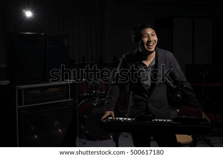 Musician playing keyboard with music instrument and lens flare from spot light on dark background, Musician concept