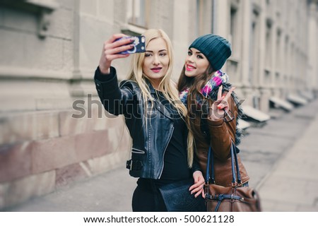 two beautiful girls are photographed on the street in hats and classy jackets