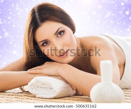 Young, healthy and beautiful girl relaxing in winter spa salon. Massage therapy, healing medicine and health care concept. Christmas background.