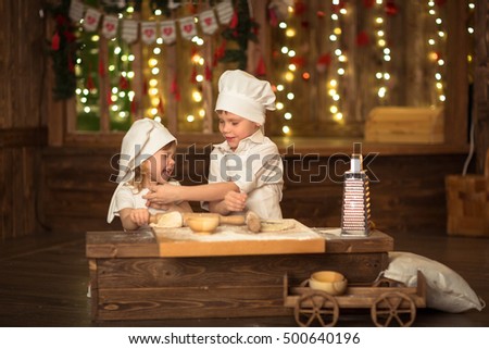 brother and sister baked, the dough is rolled out, the concept of mother's little helpers cook independence. Dark background, lights