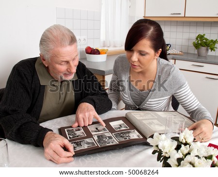 A young woman looks at a photo album with seniors