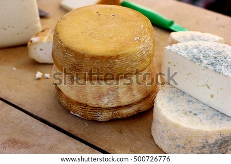 Rural farm natural organic cheese cut on wooded background. Country style handmade cheeses farm market concept. 
