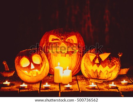 Halloween pumpkins head jack lantern with candles around on the old boards in a spooky night landscape. Soft focus. Shallow DOF
