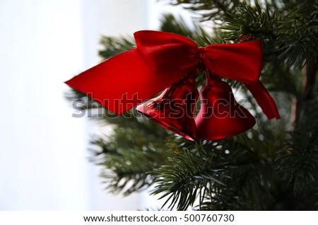 Close up of Fir tree branch and traditional large glitter red bells and bow. Christmas or New Year concept. Winter festive background. Copy space.
