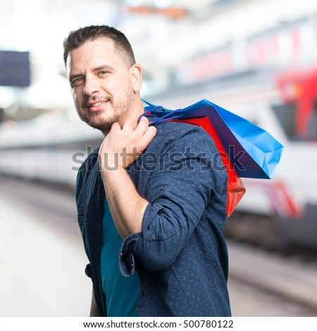 Young man wearing a blue outfit. Holding shopping bags.
