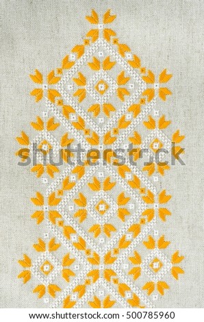 Embroidery design by yellow and white cotton threads on flax. Geometric ornament. Background with embroidery. Royalty-Free Stock Photo #500785960