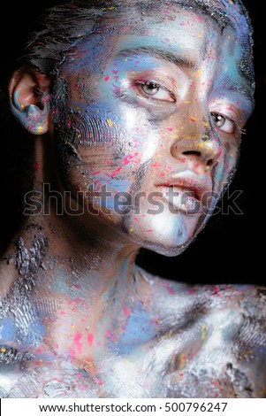 Portrait of a woman with colorful paint brushstroken on face. Bright blue eyes. Advertising Space