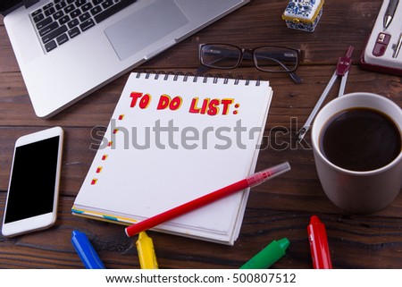 To do list concept mock up: note books, red marker, cup of coffee, tablet, laptop, calculator and stationery on brown wooden background