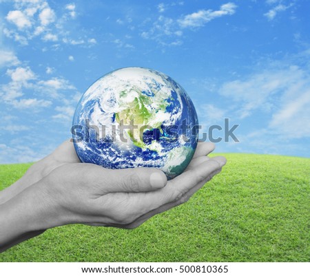 Earth in black and white hands over green grass with blue sky and clouds, Environment concept, Elements of this image furnished by NASA