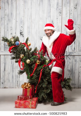 Picture of Bad Santa Clause waving to all while riding on Christmas tree iolated on white background. New Year concept.