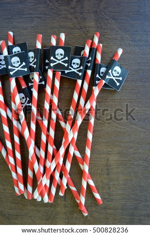 Red and White striped Navy or Pirate party themed straws on a wood background texture