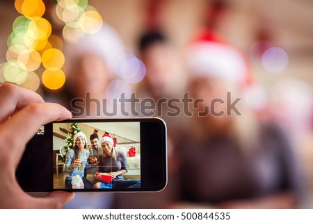 Taking picture of friends at Christmas eve with smart phone.