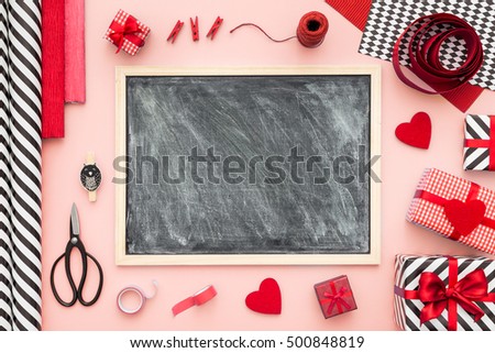 Blackboard and presents wrapped on a mint color background with different on a pink color table. Flat lay.Christmas (xmas) or New year gift packing. Holiday decor concept.