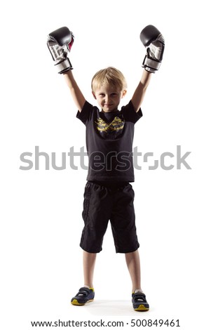 blond little boy boxer with boxing gloves standing in a defensive posture. dressed in a black T-shirt and shorts. photographed in the studio with backlit, isolated on white background