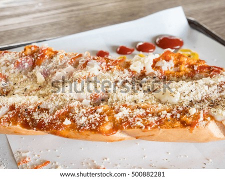 sausage and bacon pizza in tray on wooden table