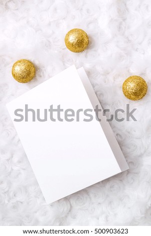 Mockup. White card, golden Christmas balls arranged on a white fur.