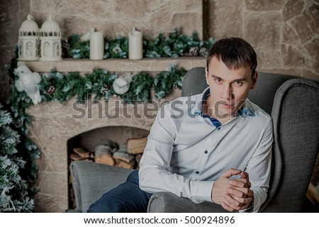young man sitting on background of Christmas interior