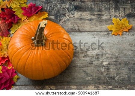 Pumpkin and autumn leaves on wooden background

