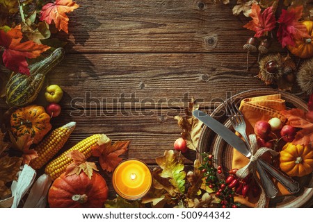 Autumn background from fallen leaves, fruits with vintage place setting and burning candle on old wooden table. Thanksgiving day concept