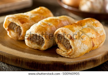 Delicious homemade sausage rolls on a wooden serving platter. Royalty-Free Stock Photo #500960905