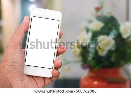Hand holding mobile smart phone with blank screen in vertical position, blurred people background - mockup template