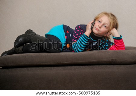 Cute little caucasian blonde blue eyed girl uses a smartphone, 