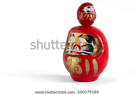 Two red Daruma dolls, a small one on top of a bigger one, with the typical missing eye,  standing on the left of the picture, facing opposite directions, on a white background.