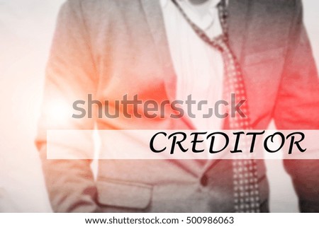 Hand writing CREDITOR with the young business man on background. Business concept. Stock Photo.