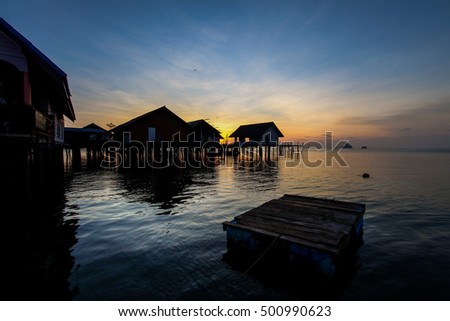 silhouette wooden village on sea sunset sky