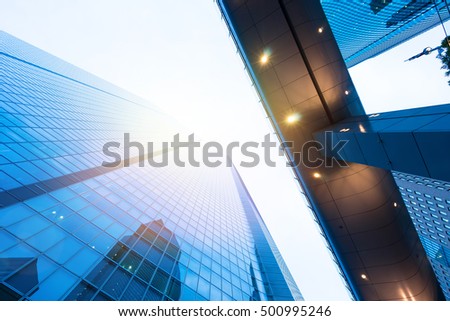 Business concept for real estate and corporate construction - looking up view in financial district, the silhouettes of skyscrapers city reflect blue sky, sun lights in Tokyo, Japan