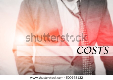 Hand writing COSTS with the young business man on background. Business concept. Stock Photo.