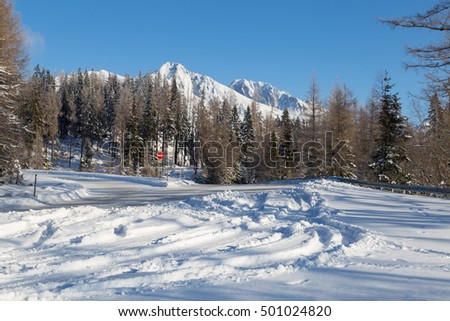 Winter snow covered road with view of  snowy peaks mountains against the blue sky. Turning to the famous ski resort of Strbske Pleso. High Tatras. Slovakia.
