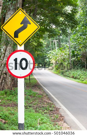 Selective speed limit traffic sign 10 and winding road caution symbol for safety drive in country road in mountain view forest,low key
