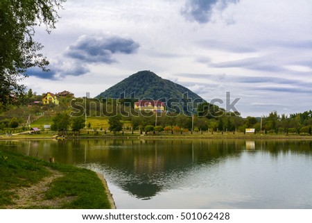 Houses on the shore of the lake. Mountain lake for fishing against the background of green vegetation, blue morning sky in cirrus clouds and the rising sun. Early morning. Western Ukraine.