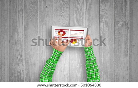 Top view of girl hands using tablet pc with diagrams and graphs on screen