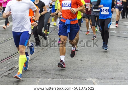 Marathon runners race in city streets, blurred motion