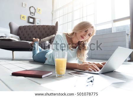 Blond woman lying on floor and using laptop