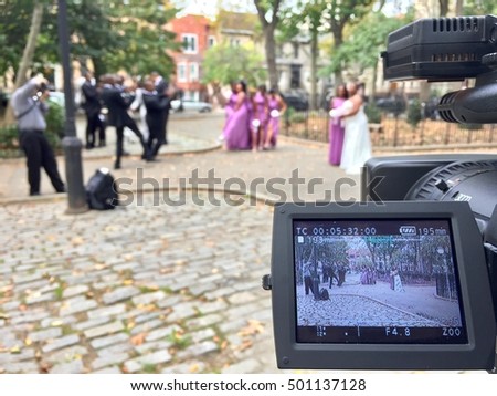 Behind the scenes of a videocamera taping a wedding party and beautiful bride and her family and friends before celebration reception. Event photography