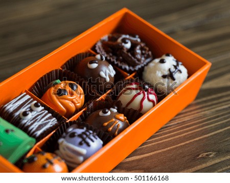 Orange pumpkin for halloween and Different kind of Monster chocolate in the orange box on wooden table in retro style ,with copyspace.