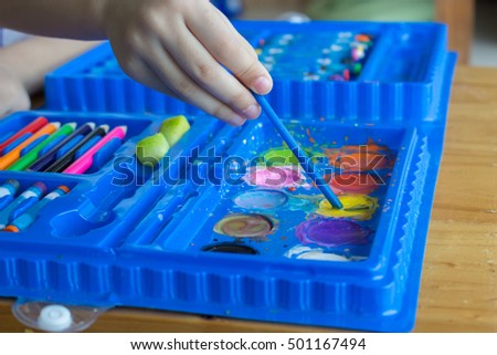 water color in blue pallet ,color set for kid ,child use a brush dip in yellow color
