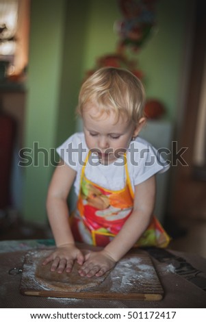 little girl baking cookies, rolls the dough