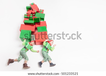 Funny two boys dressed in Elf costumes holding many gift boxes. Black Friday 2016! Celebrating Christmas. Copy space at white background. Big gift box! Cristmas shopping. Merry Christmas! Big Sales