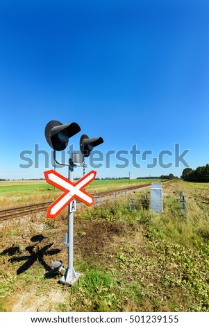 Railway crossing equipped with electric lights. Crossing the road in the countryside.