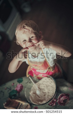 little girl baking cookies. Flour stirred in a cup