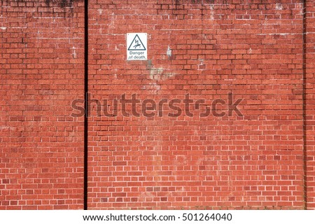 Red brick wall with a warning sign of high voltage danger