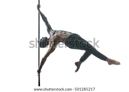 Perfect pole dancer with horrific body-art hangs horizontal on a pylon in the studio on the white background. He wears black pants. Guy holds the pylon with his stretched hands. Horizontal. 