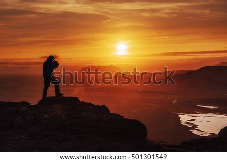 Happy man standing on a cliff at sunset.

