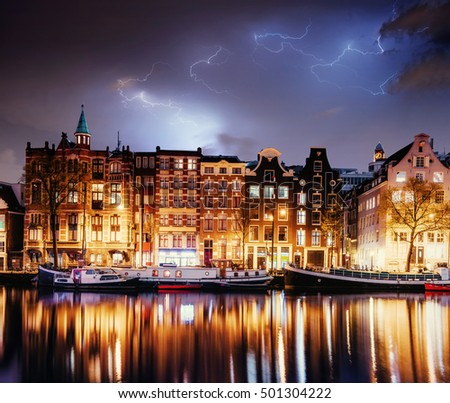 Fantastic collage. Beautiful lightning. Night in Amsterdam. Highlighting buildings and boats near the water in the channel. Art photography.