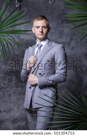 Full length of thoughtful bridegroom standing amidst flower decorations